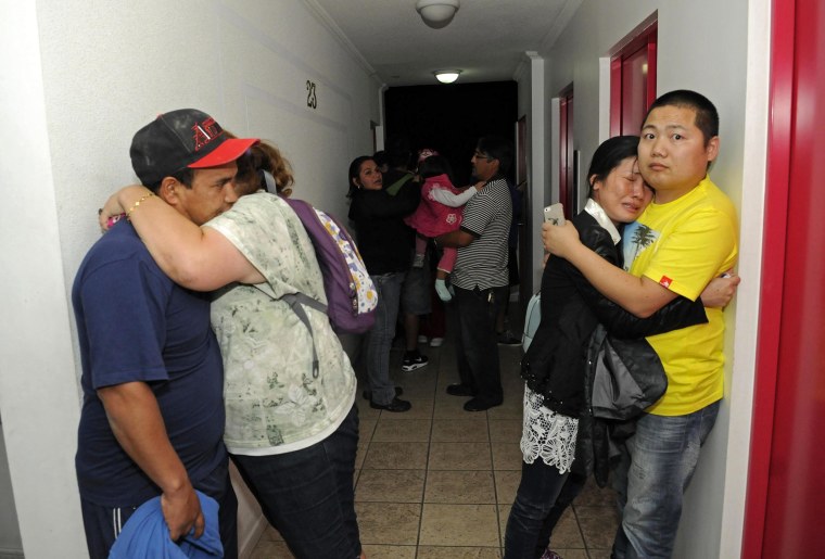Image: People embrace on the upper floor of an apartment building located a few blocks from the coast where they gathered to avoid a possible tsunami