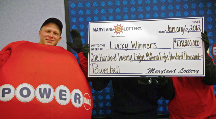 A man dressed as a Powerball stands by winners who did not want to be identified as they hold a large prop check showing their winnings at the Maryland State Lottery headquarters in 2012.