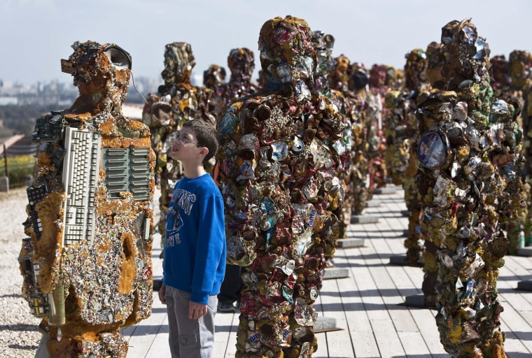 Image: A boy looks at a statue by German artist HA Schult during a preview of the artist's exhibition at the Ariel Sharon Park near Tel Aviv