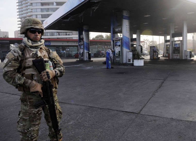 Image: A soldier guards a gasoline station after a tsunami hit the northern port of Iquique