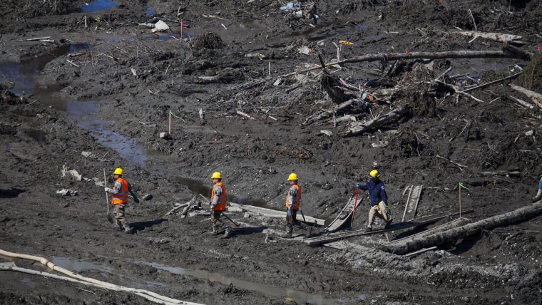 Image: Workers cross the site of the mudslide near Oso, Wash., where 27 are now confirmed to have died.