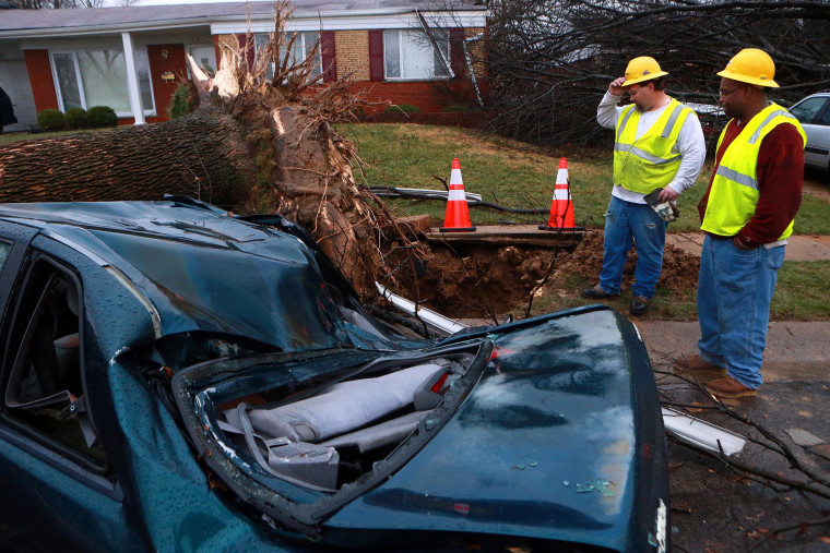 Image: Jason Reidl, left, and Chris Thomas with Laclede Gas, look at a fallen tree that ruptured a gas main in University City, Mo.