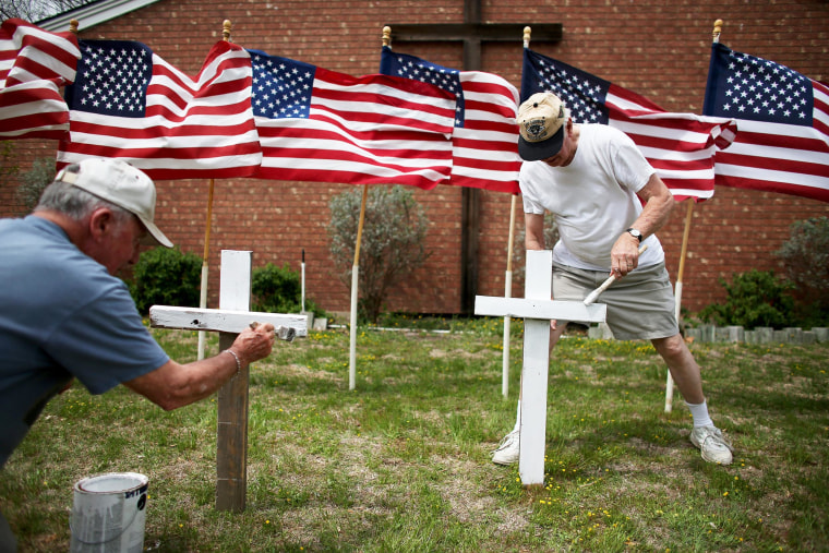 Image: Bob Gordon, left, and Bob Butler paint crosses they placed in front of 16 American flags as they build a memorial in front of Central Christian Disciples of Christ church for the victims of yesterday's shooting at Fort Hood