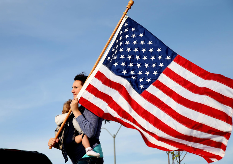 Image: Mellissa Phillips holds Sierra Phillips as she and others participate in a flag walk in memory of those killed and injured by Iraq war veteran, Ivan Lopez, in Killeen, Texas