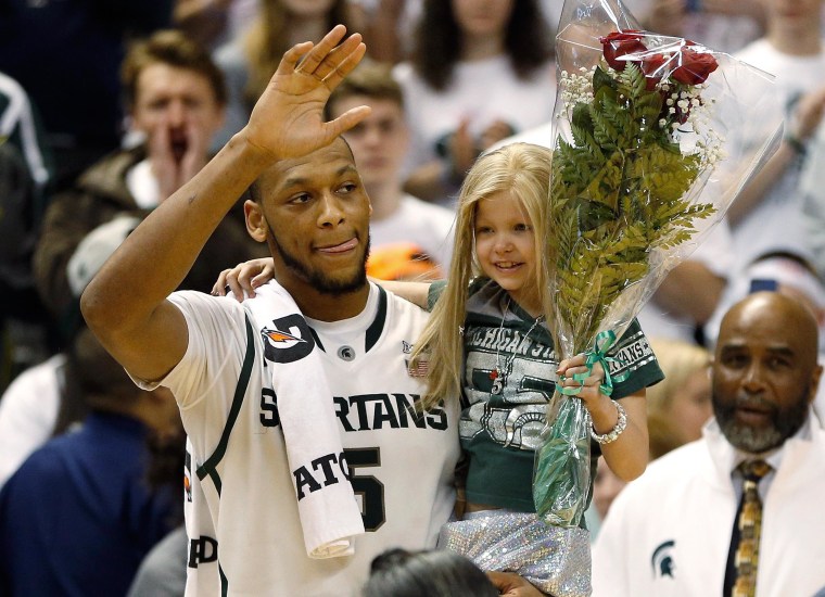 Adreian Payne #5 of the Michigan State Spartans walks on the floor for Senior night with Lacey Holsworth, a 8-year-old from St. Johns Michigan who is battling cancer, after defeating the Iowa Hawkeyes 86-76 at the Jack T. Breslin Student Events Center on February 6, 2014 in East Lansing, Mich.