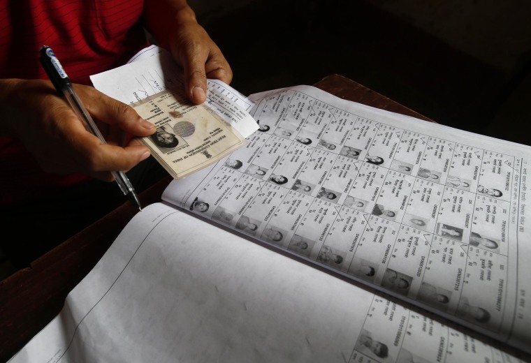 Image: Election official checks voter's identity in Agartala, India