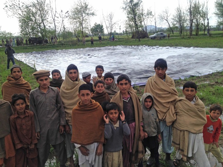 Children gather around the poster bearing the image of a Pakistani girl whose parents, lawyers say, were killed in a drone strike, in a field at an undisclosed location in the northwestern Khyber-Pakhtunkhwa province of Pakistan.