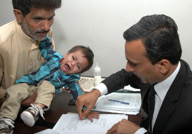 Image: A Pakistani lawyer taking the thumb impression from nine-month-old toddler Mohammad Musa