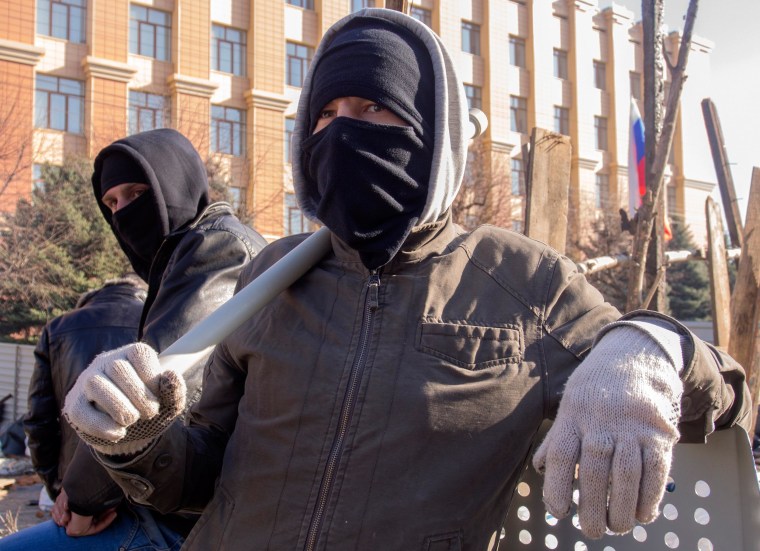 Image: Pro-Russian activists in face masks stand near a barricade in front of an entrance of the Ukrainian regional office of the Security Service in Luhansk