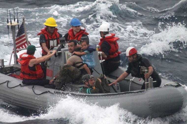Image: Sailors assist in the rescue of a family with a sick infant via the ship's small boat as part of a joint U.S. Navy, Coast Guard and California Air National Guard rescue effort
