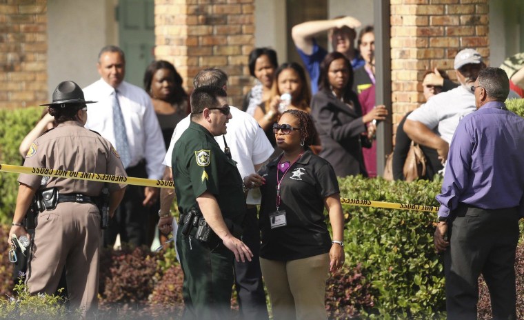 Image: Parents wait behind as police consult after several children were injured after being struck by a vehicle at a KinderCare Learning Center in Winter Park