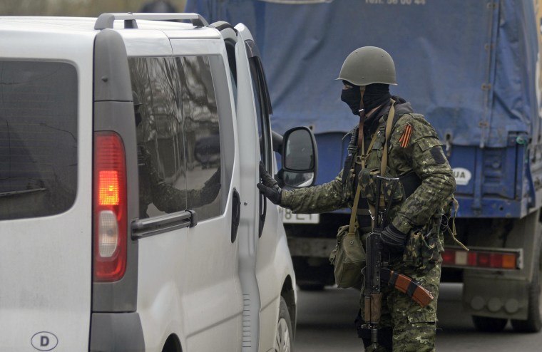 Image: An armed man inspects a car at an improvised checkpoint in Slaviansk