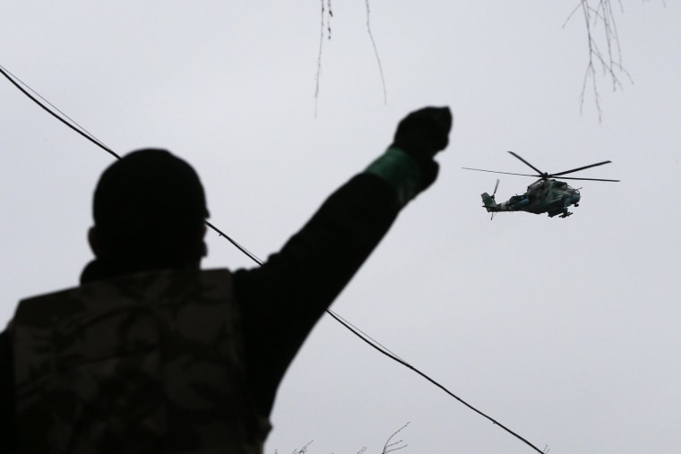 Image: A man gestures while pro-Russian protesters gather at the police headquarters, while a military helicopter flies above, in Slaviansk