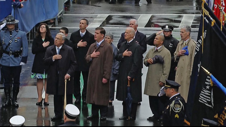 Officials, including Vice President Joe Biden, center right, and Massachusetts Governor Deval Patrick, second from right, cover their hearts with their hands during a flag-raising to mark the anniversary of the Boston Marathon bombings.