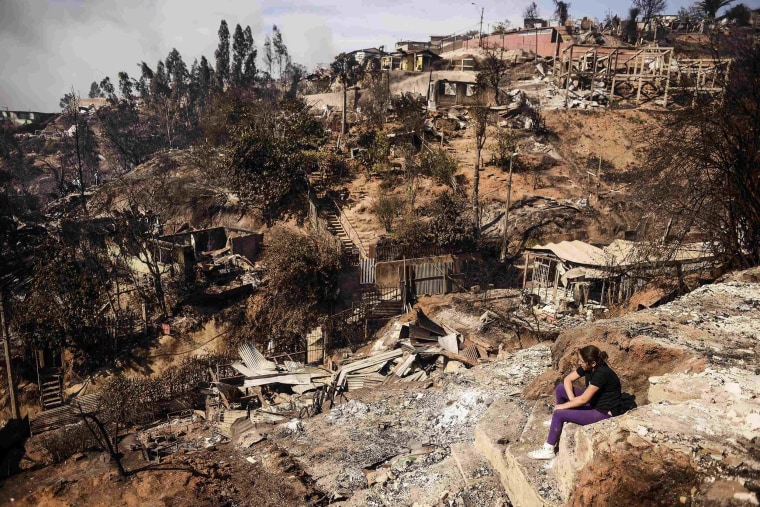 Image: A resident whose home was destroyed by major fire sits amid destruction in Valparaiso