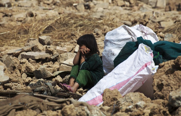 Image: An Afghan refugee girl sits with her belongings after authorities razed her house in the slums of Islamabad