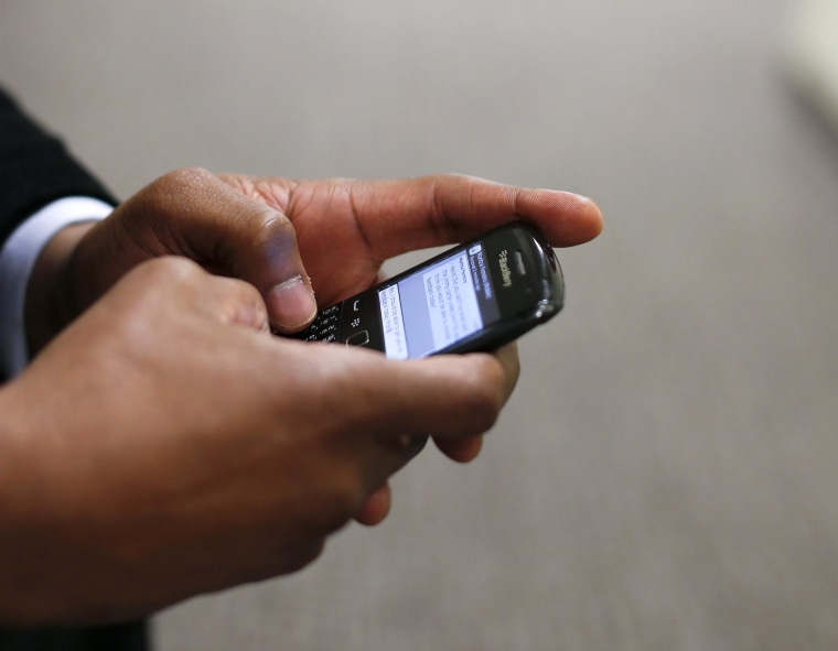 Image: A man uses his Blackberry mobile device to write a text message
