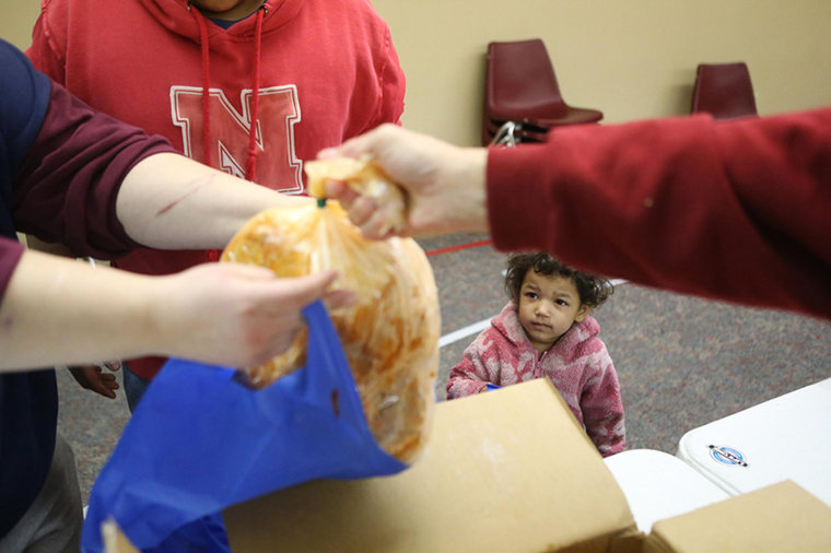 Image: Olivia Grimes, 3, watches a food line volunteer hand a turkey to her mother Jaime in Lincoln, Nebraska.