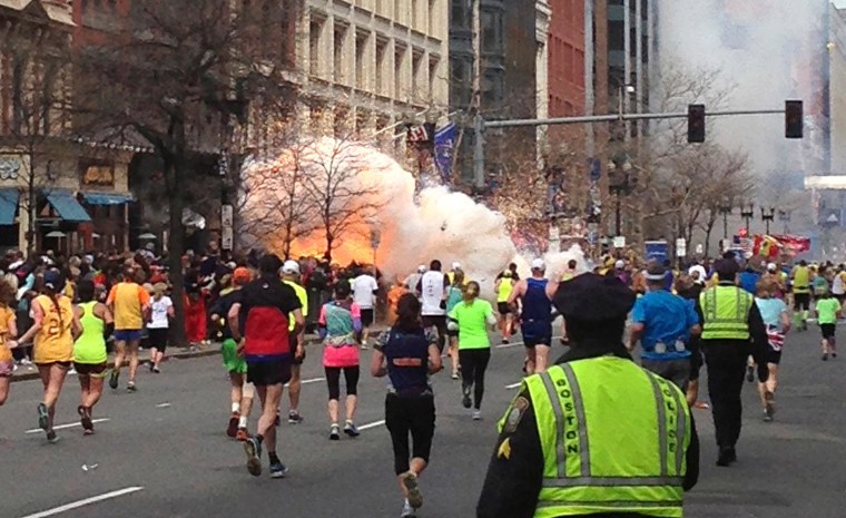 Image: Runners run towards the finish line as an explosion erupts at the finish line of the Boston Marathon