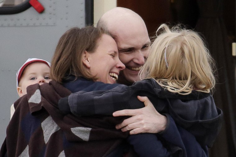 Image: French journalist Henin, former hostage, is greeted by his family moments after arrival of four former hostages by helicopter from Evreux to military airbase in Villacoublay, near Paris