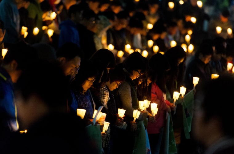 Image: People hold candles at a vigil for missing students who were onboard the South Korean capsized ferry on April 22.