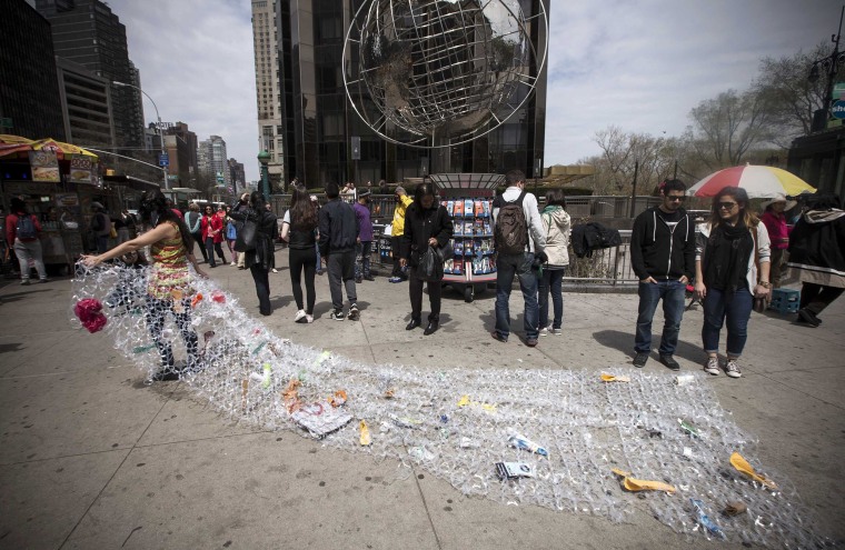 Image: Bianca Cortinas carries a sheet of plastic six pack rings and trash during a demonstration to mark Earth Day in Manhattan in New York City