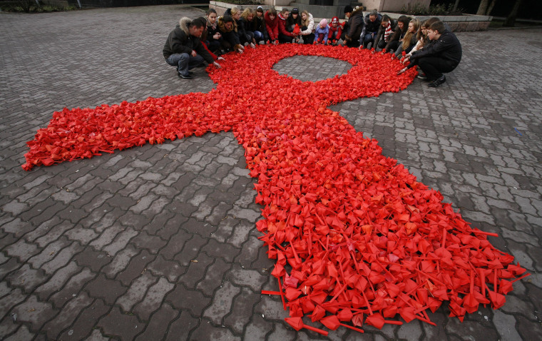 Activists form a red ribbon, the symbol of the worldwide campaign against AIDS, made from paper tulips as they take part in the campaign and also mark International Volunteers' Day in the city of Rostov-on-Don