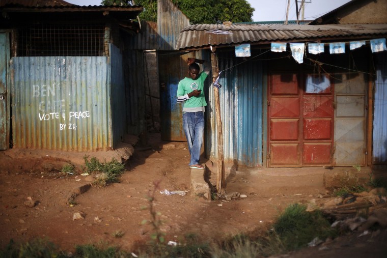 Image: A man checks his phone in Kibera, Kenya