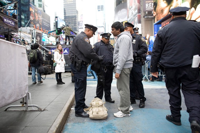 New York City Police Department officers search the bag of a man in Times Square.