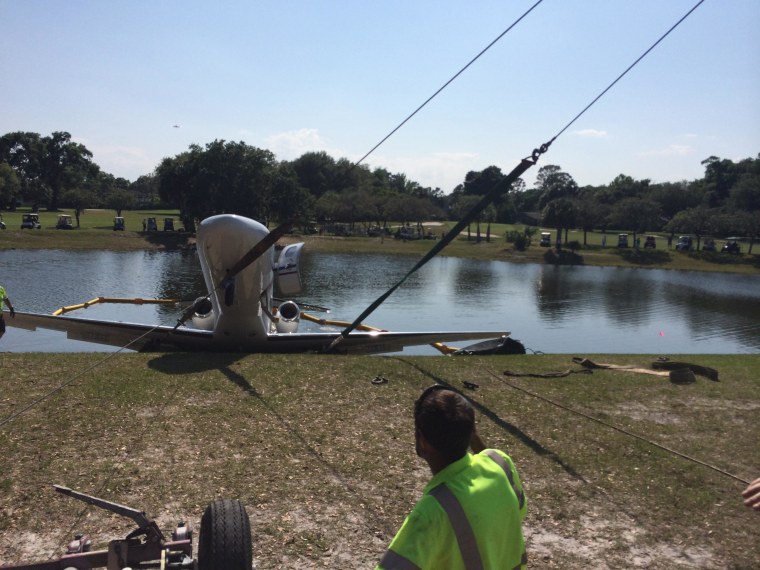 Image: A worker looks on as a plane is towed out of a pond in Volusia County, Fla.