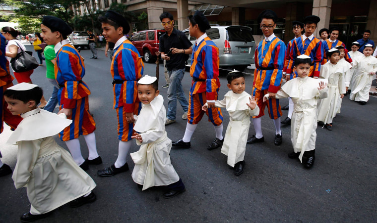 Image: Children wearing Pope's cassocks cross a road before taking part in a parade in Quezon city