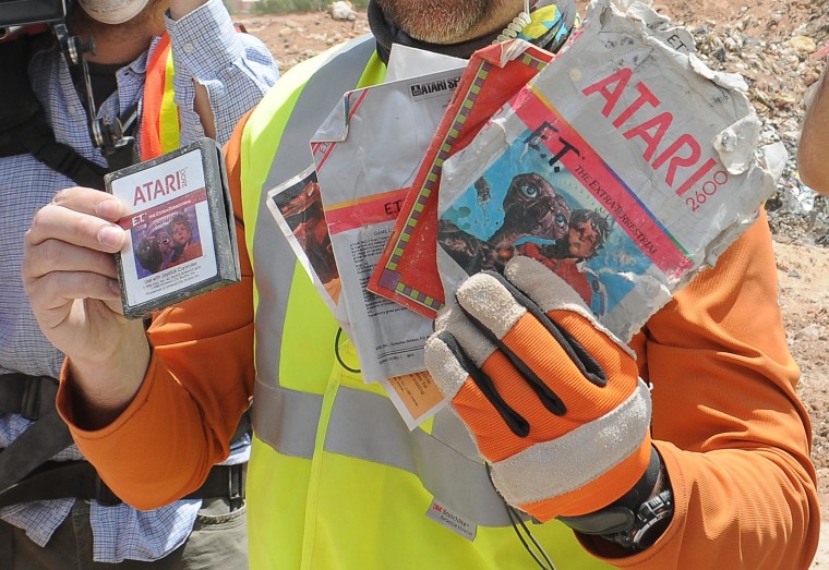 Image: A worker shows the media the first recovered "E.T. the Extra-Terrestrial" cartridge at the old Alamogordo landfill in Alamogordo