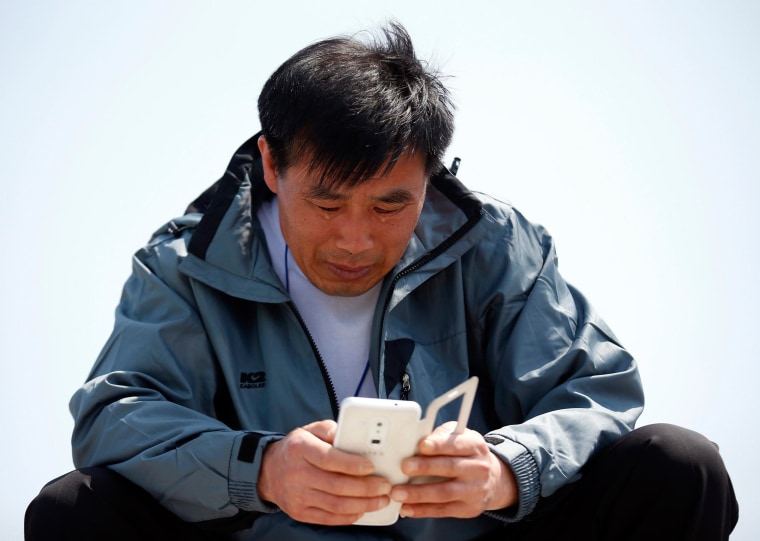 Image: Family member of a missing passenger onboard capsized Sewol ferry, cries while looking at a mobile device, at a port in Jindo