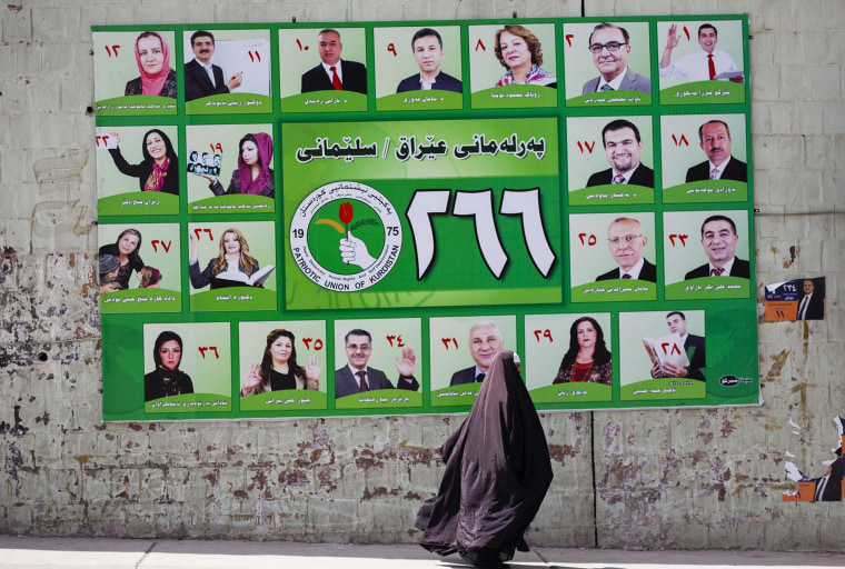 Image: A woman walks past a PUK campaign poster for Iraq's parliamentary elections in Sulaimaniya