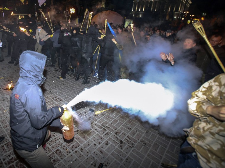 Image: A man uses a fire extinguisher as members of self-defence units of the Euromaidan movement attempt to prevent members and supporters of Ukrainian far-right radical groups from taking part in a torch-light procession in Kiev
