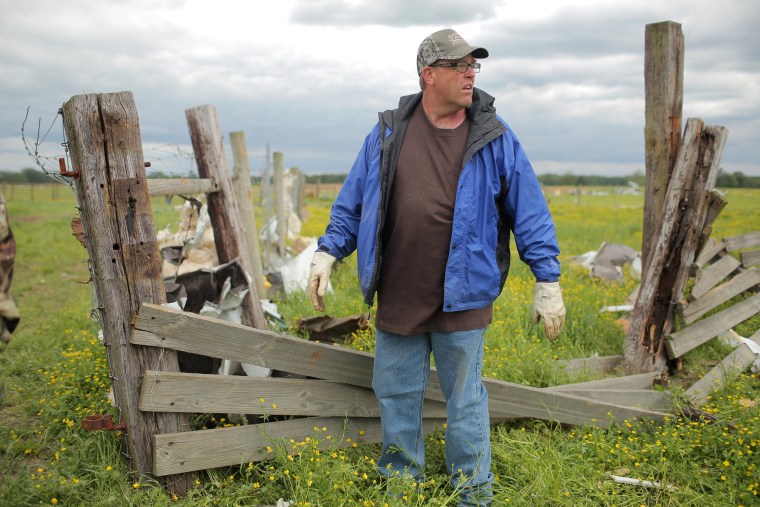 Image: Cattle rancher Preston Scroggin cleans up a corral destroyed by Sunday's tornado at his farm in Vilonia, Ark.