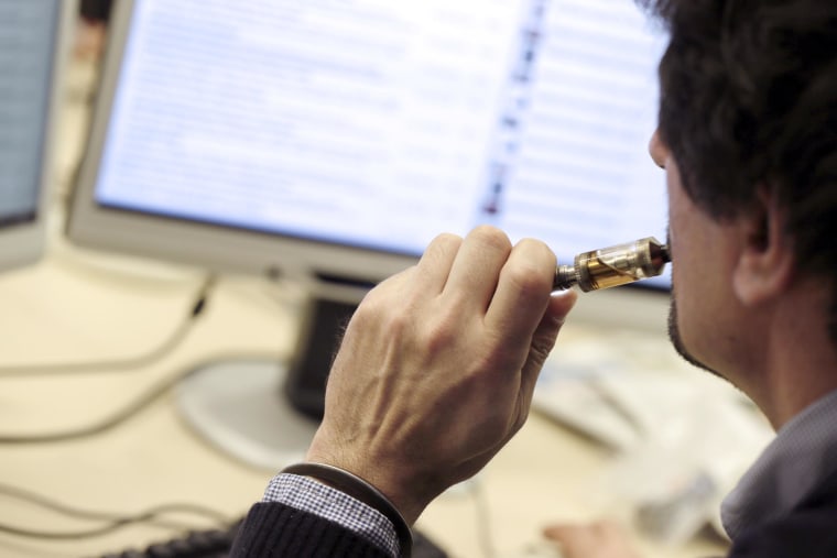 A man smokes an electronic cigarette in his office.
