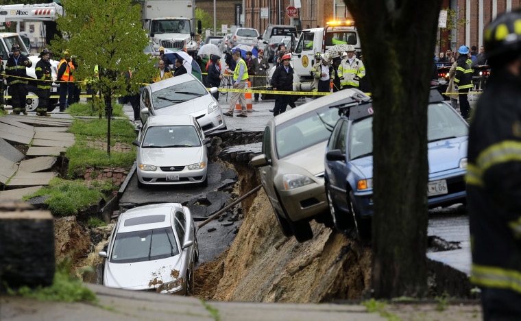 Image: Cars sit on the edge of a sinkhole in the Charles Village neighborhood of Baltimore