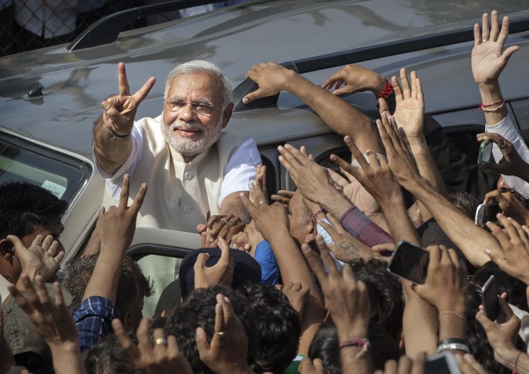 Image: BJP leader Narendra Modi shows his inked finger to supporters as he leaves a polling station