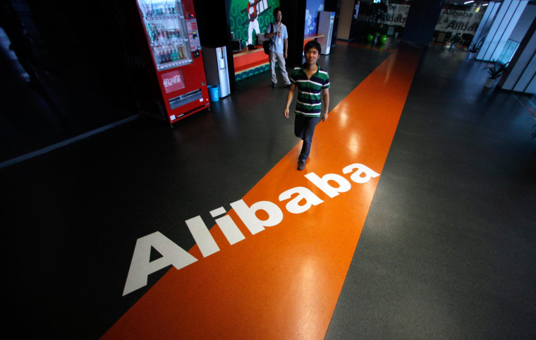 Image: An employee walks past a logo of Alibaba