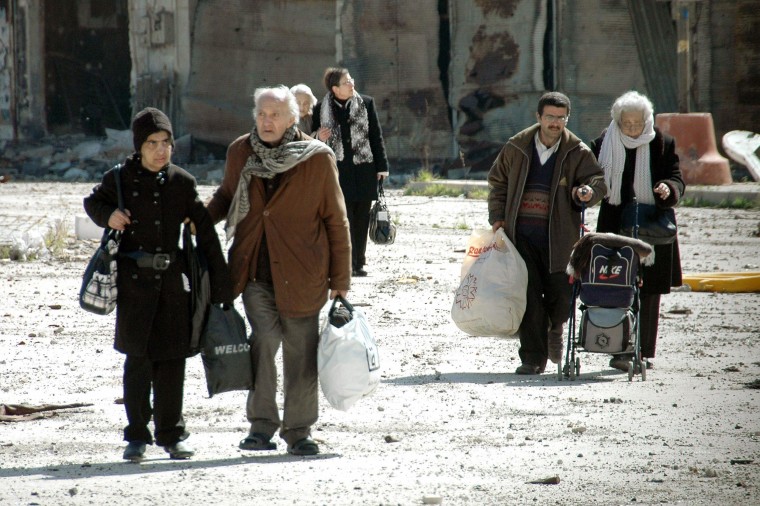 Image: Civilians carry bags during their evacuation from besieged parts of the Syrian city of Homs