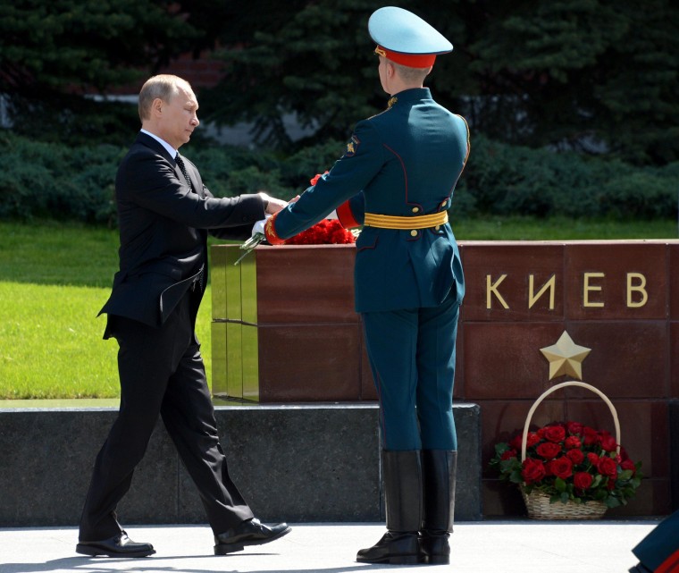 Image: Russia's President Vladimir Putin lays flowers at a polished stone block bearing the inscription Kiev, one of several honoring cities of the former Soviet Union