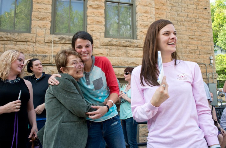 Image: Jennifer Rambo, right, smiles as her partner Kristin Seaton, center, hugs Sheryl Maples, left, the lead attorney who filed the Wright v. the State of Arkansas lawsuit