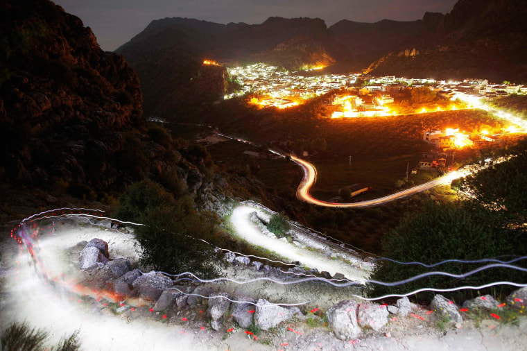 Image: Trails of headlamps are seen as runners make their way to the finish line during the XVII 101km competition on the outskirts of Montejaque