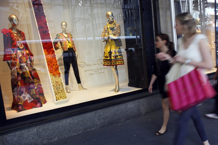 Image: Shoppers walk past the the Oscar de la Renta display at the Saks 5th Ave. retail store