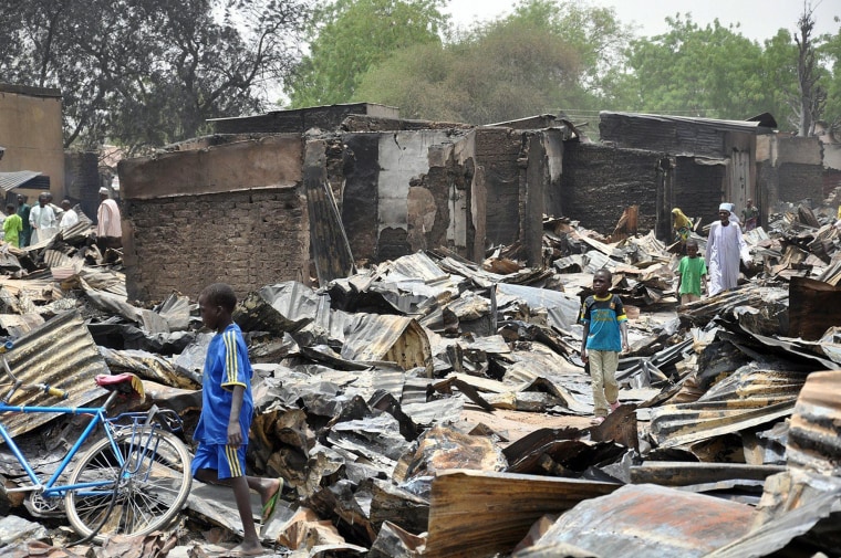 Image: A boy walks past burnt shops at Ngumborum central Market, on May 11