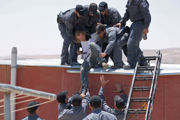 Israeli police remove a settler from the top of a house in the illegal West Bank settlement of Maale Rehavam.