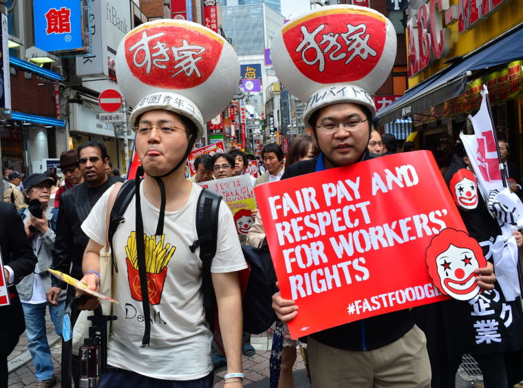 Labor union members wearing gear of Sukiya fast-food beef-bowl restaurant hold placards to demand payment of 1,500 yen (15 USD) an hour for part-time jobs during a march in Tokyo on May 15, 2014.