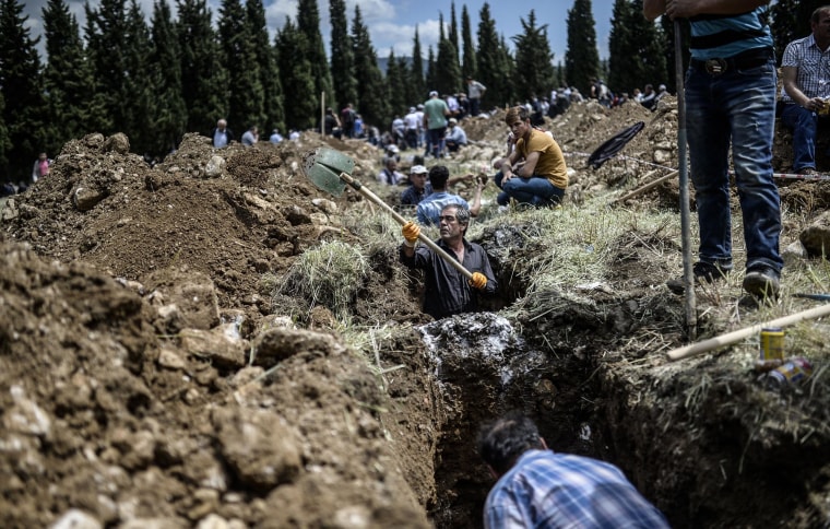 Image: People dig graves for miners killed in the Turkish town of Soma