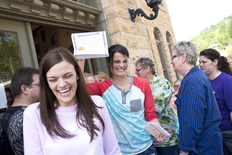 Image: Kristin Seaton holds up her marriage license as she leaves the courthouse in Eureka Springs, Ark., with her partner, Jennifer Rambo.